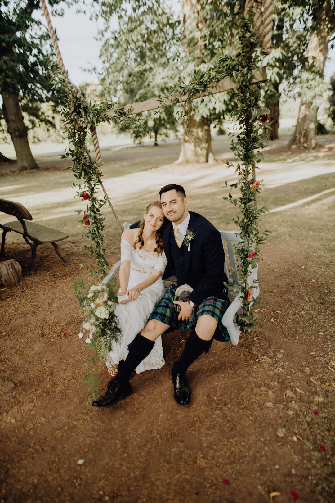 bride and groom sat on swing under large tree