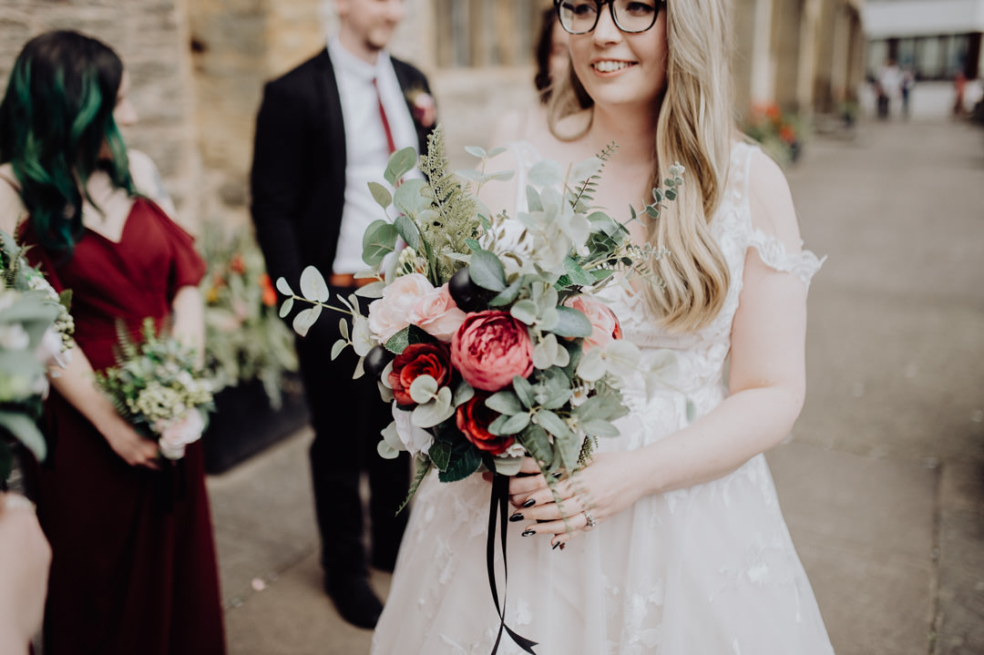 bride in white dress holding red and white flowers