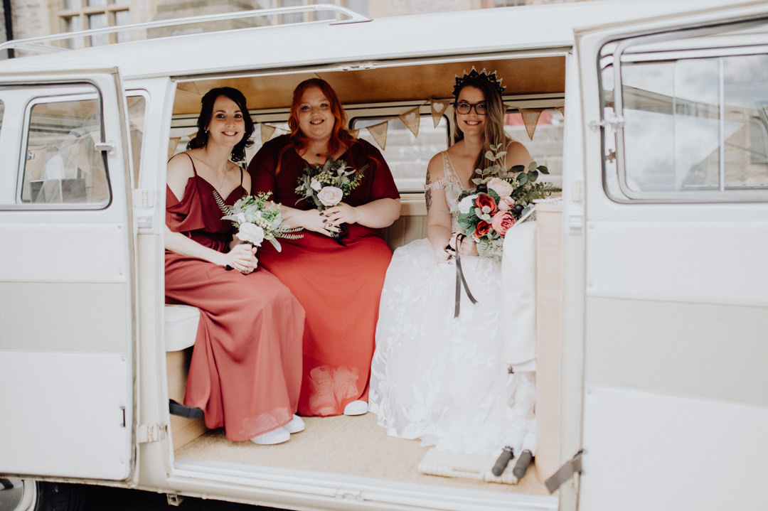 wedding bride sat in camper van holding red flowers