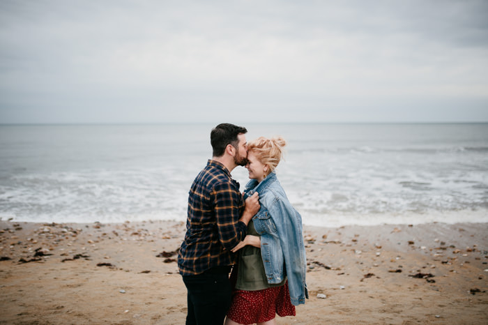 young couple stood near ocean under grey skies