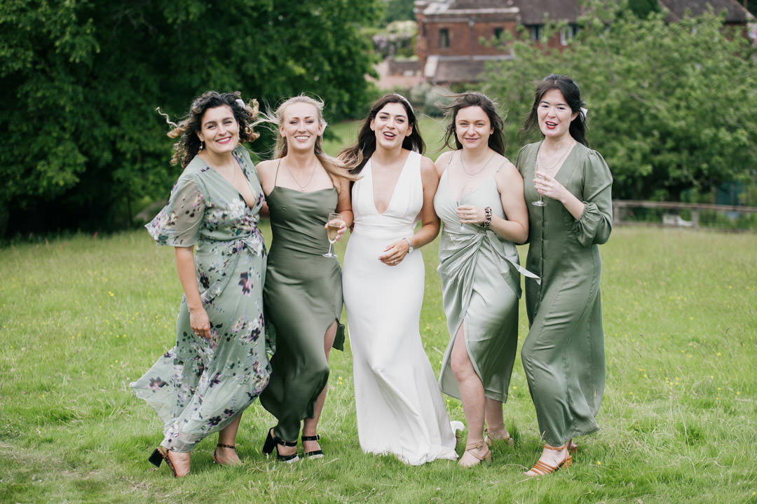 bridesmaids in green dresses holding wine glasses