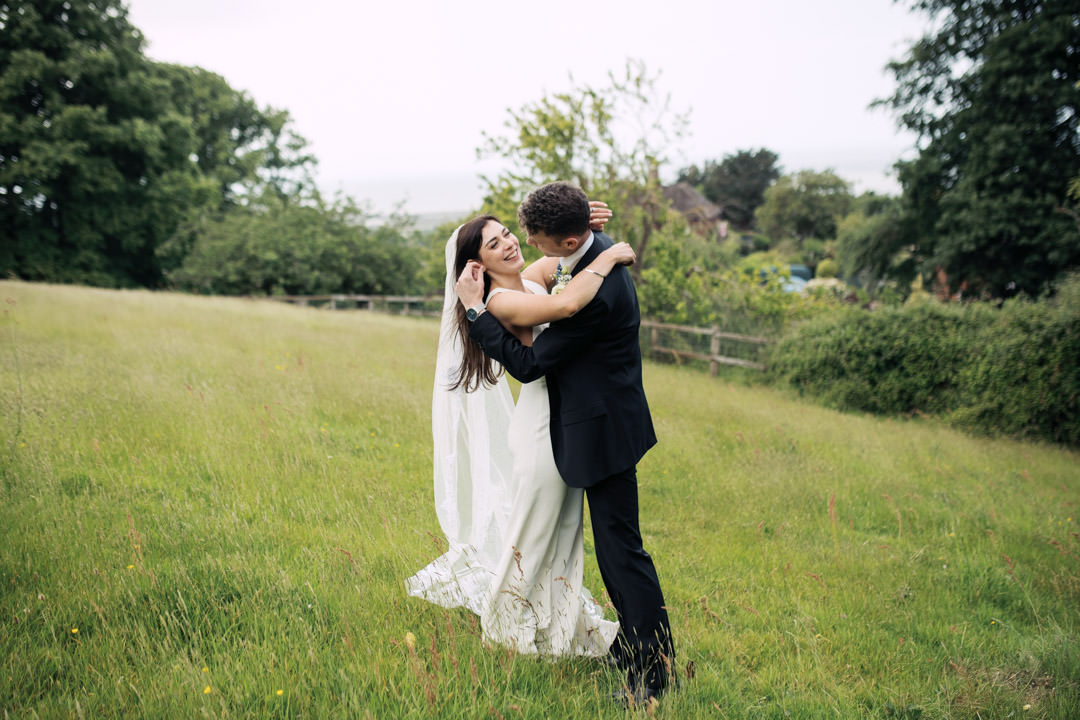 bride and groom kissing in meadow