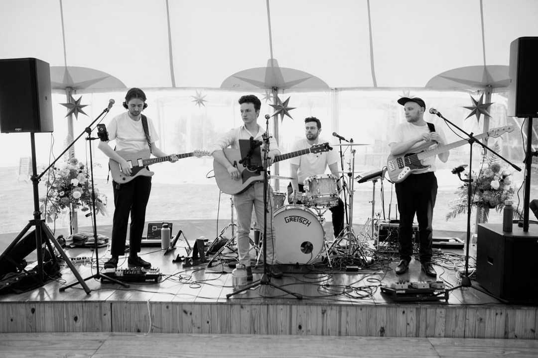 wedding band playing guitars in large tent
