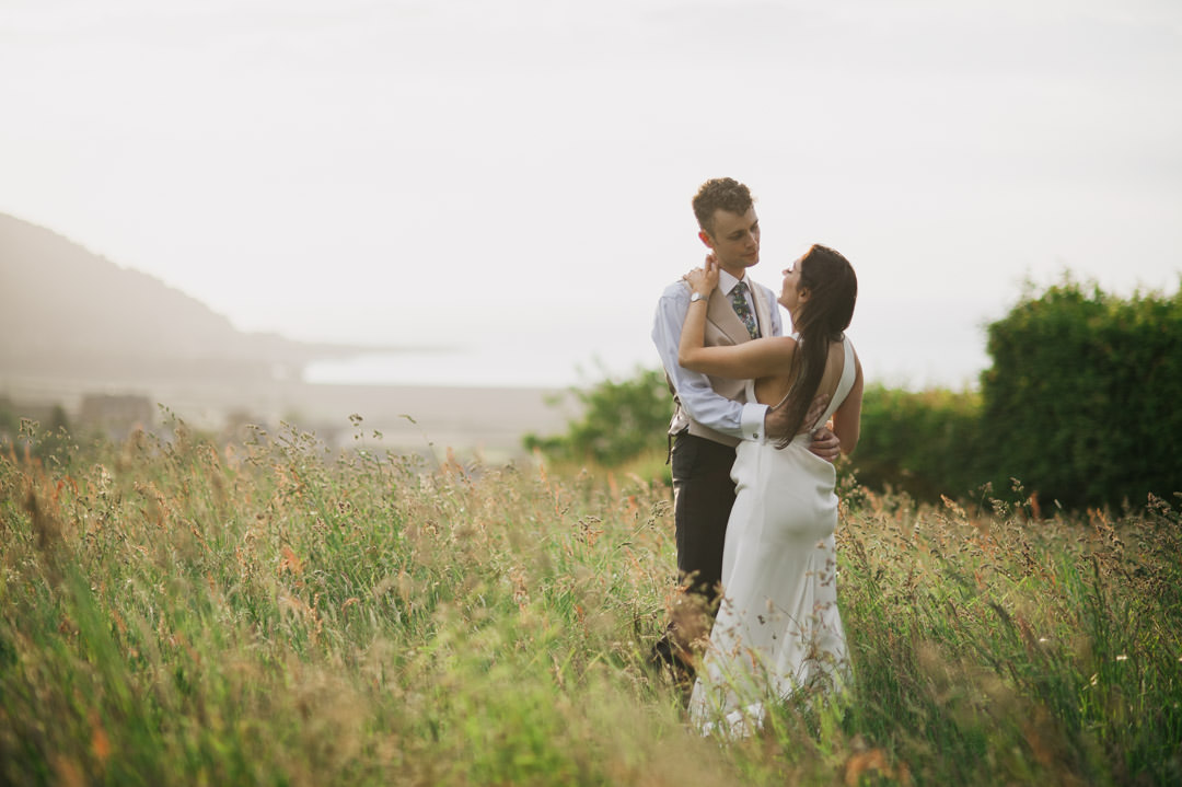 bride and groom in meadow during golden sunset