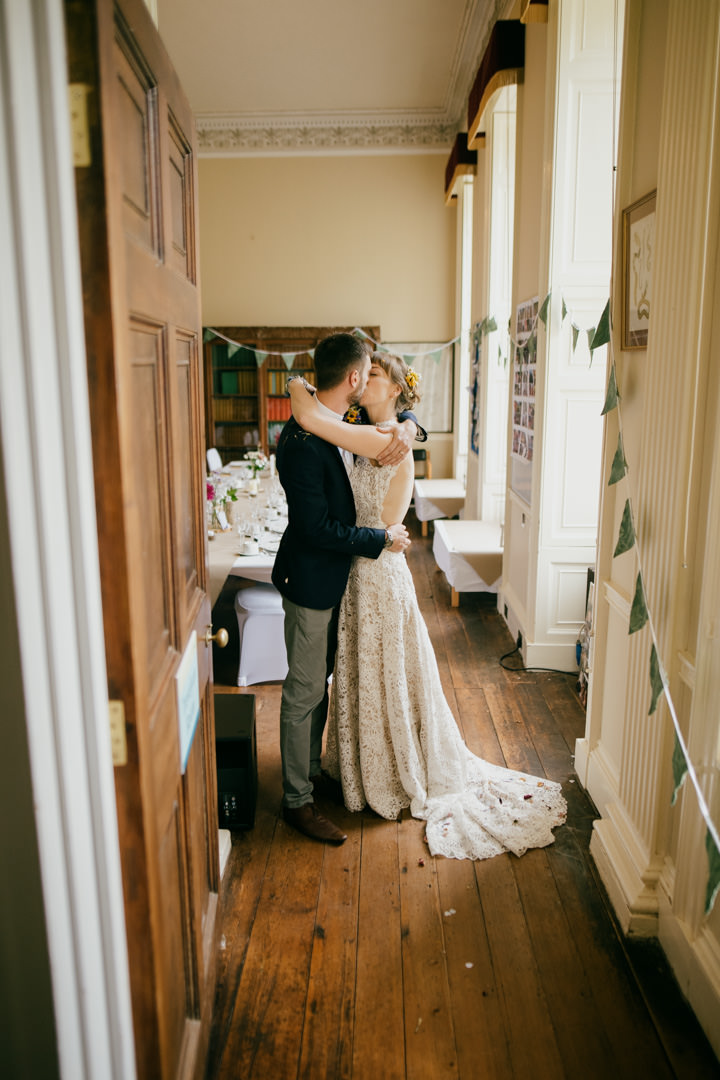 bride and groom kissing in large manor near window