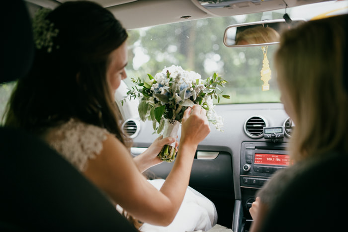 bride in car holding white flowers