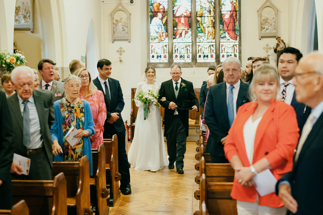 bride and father walking into church