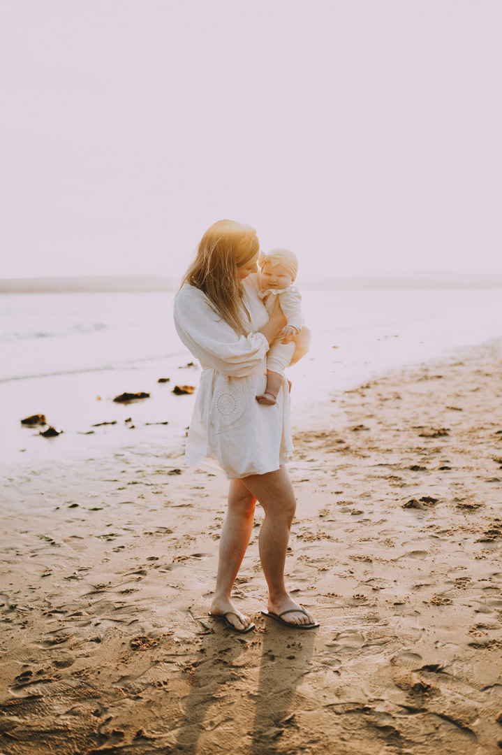 woman in white dress holding baby on beach