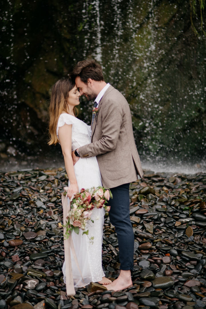 bride and groom stood near waterfall on beach in Devon