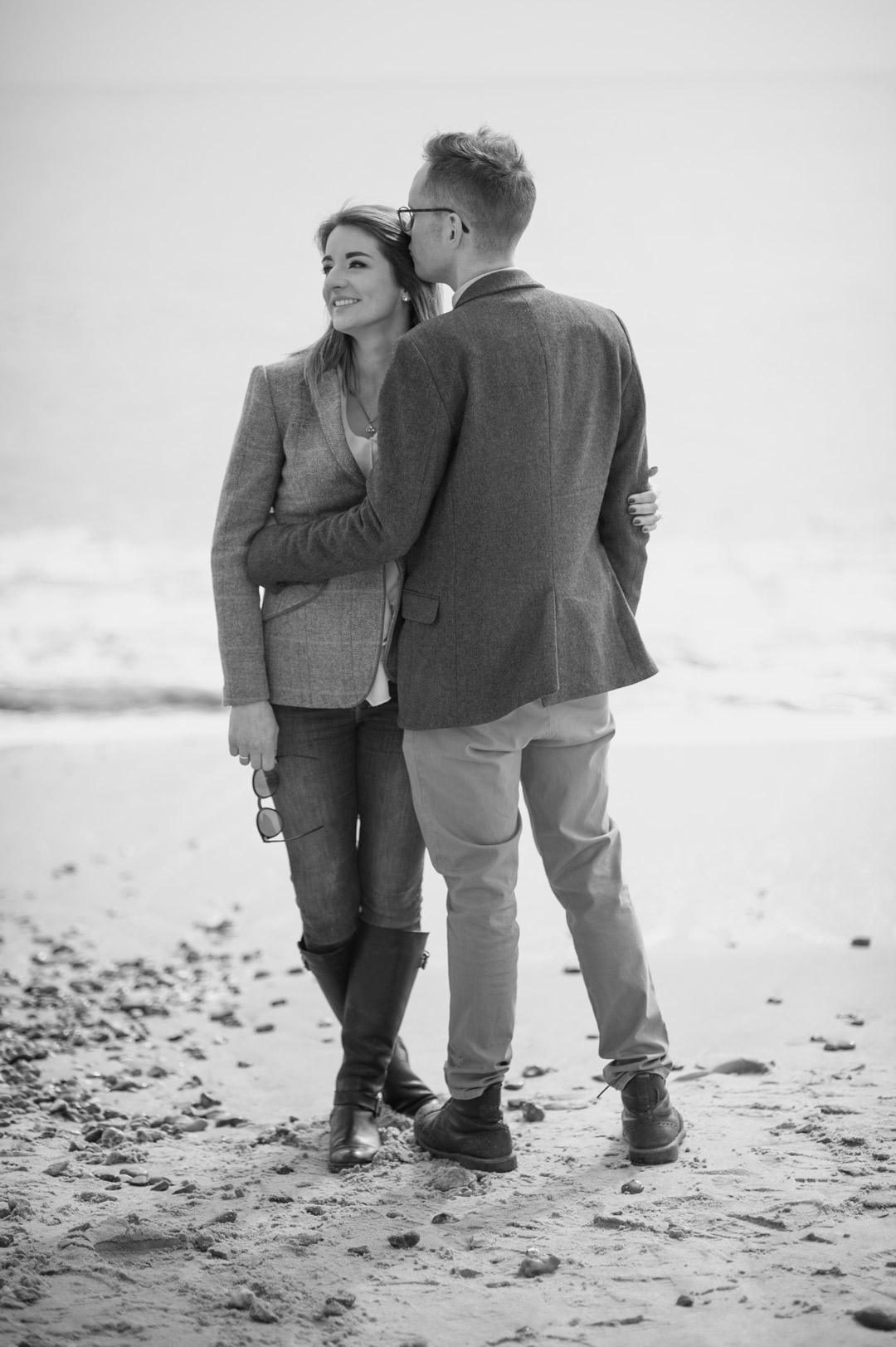 man kissing woman on cheek on beach near ocean
