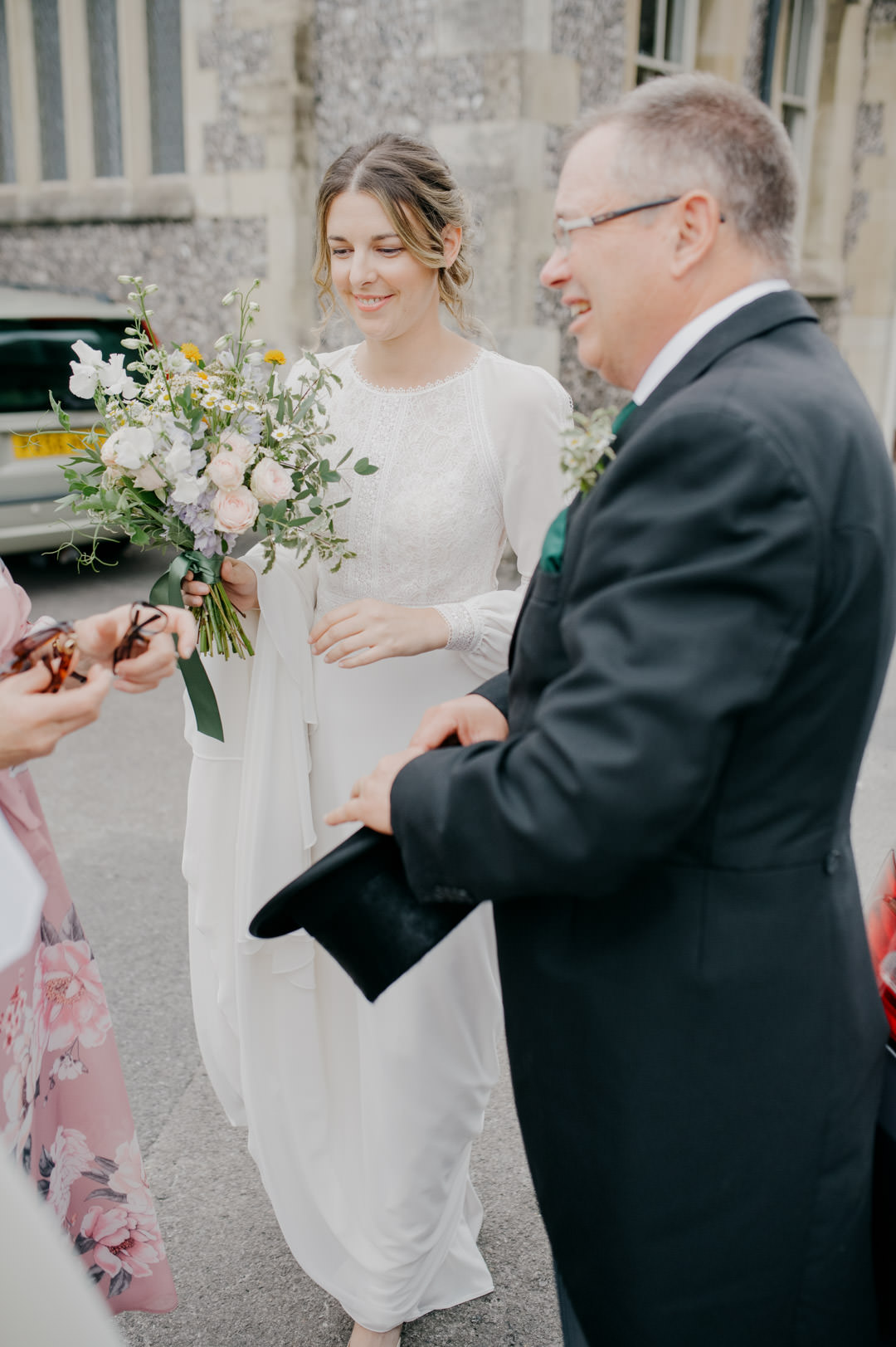 bride holding pink and white flowers standing outside church