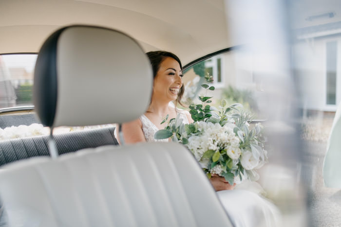bride holding flowers in wedding car