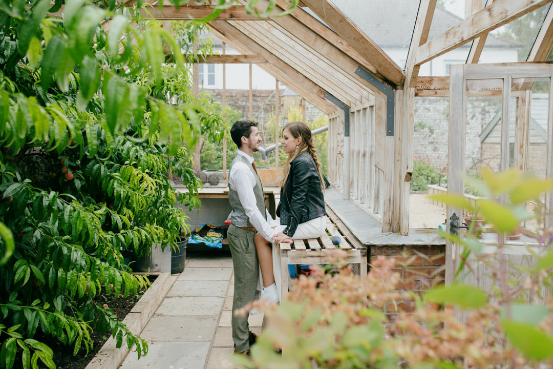 bride and groom sat in large greenhouse
