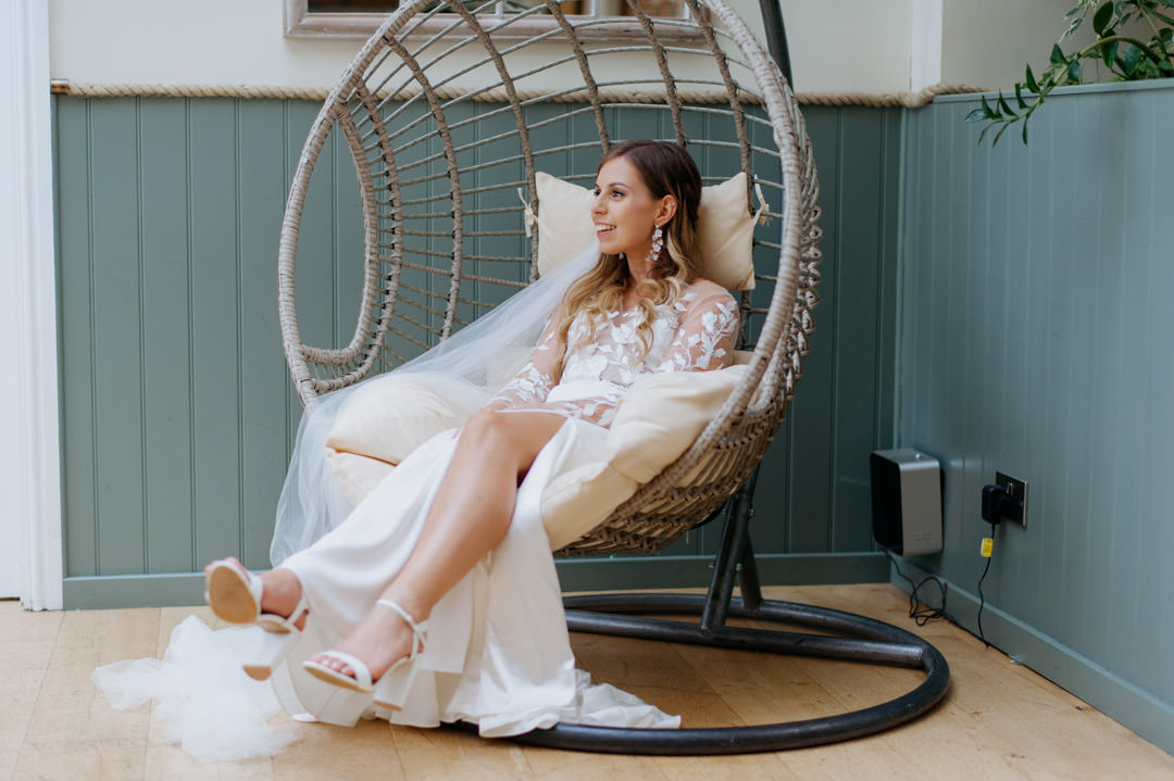 bride sat in large tub chair waring white wedding dress