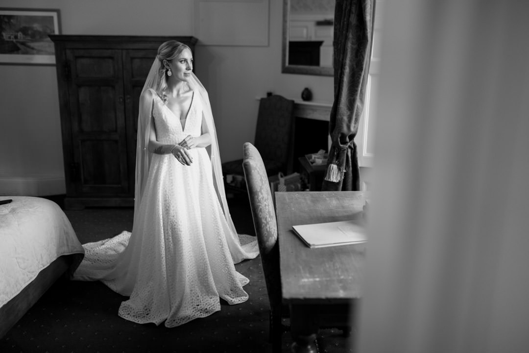 bride stood on white dress next to large window