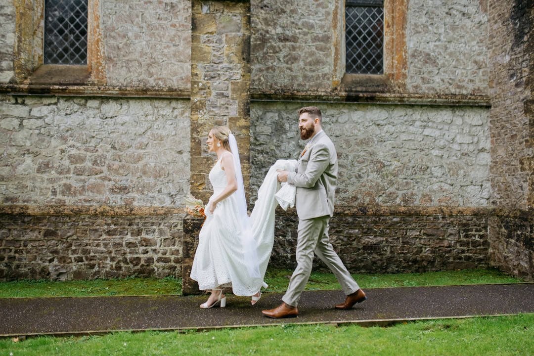 bride and groom walking through church gardens