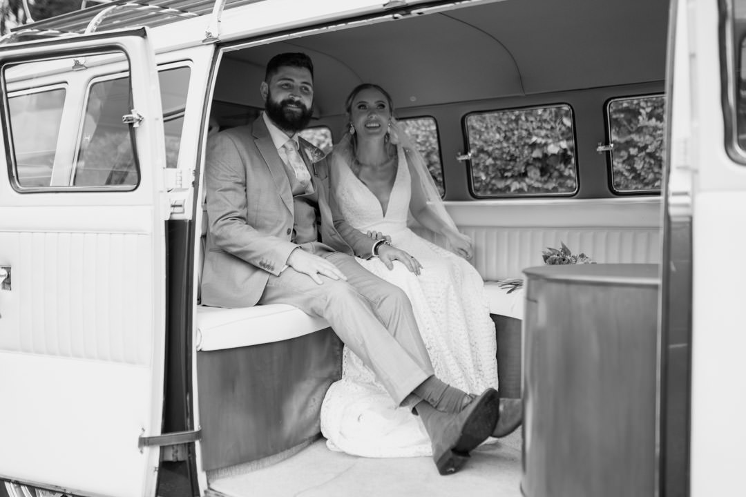 bride and groom sat in camper van smiling and laughing