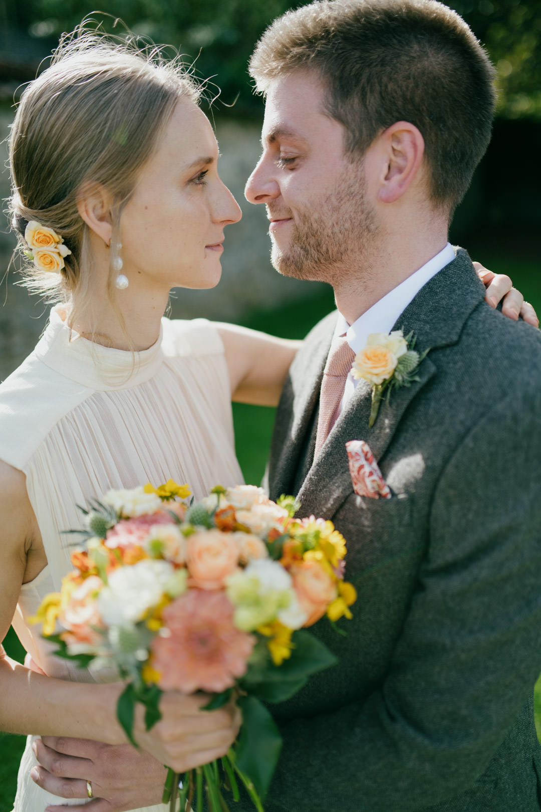 bride and groom embracing in golden sunlight holding flowers