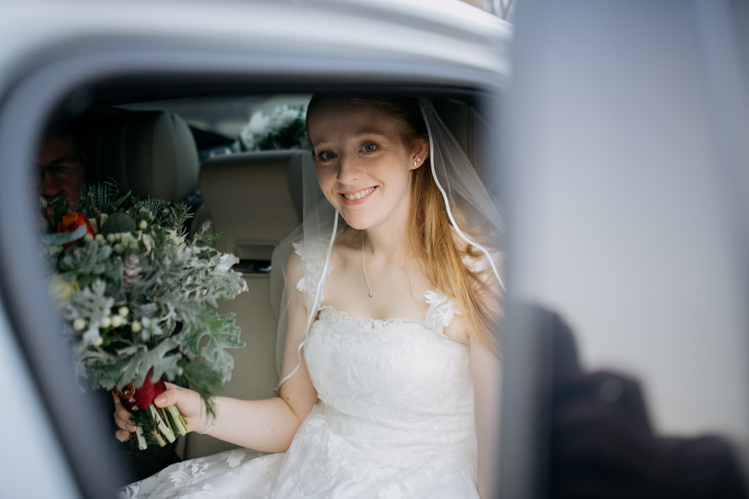 wedding bride in white car holding flowers