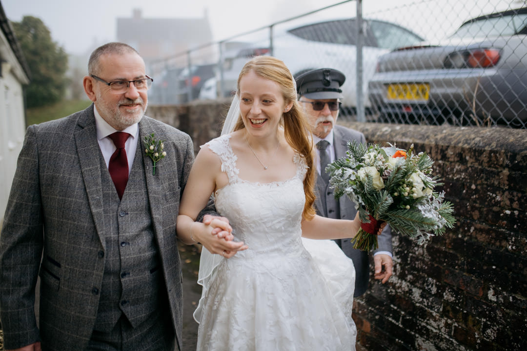 bride walking with her father holding flowers