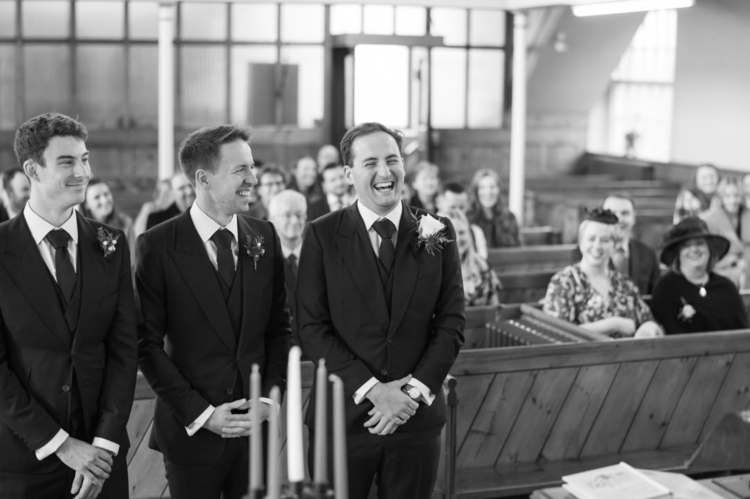 groom smiling in church waring blue suit