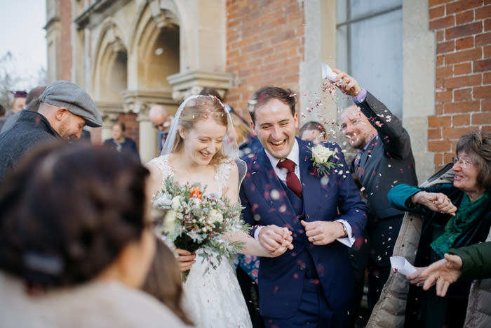 bride and groom confetti throw outside old church during day time