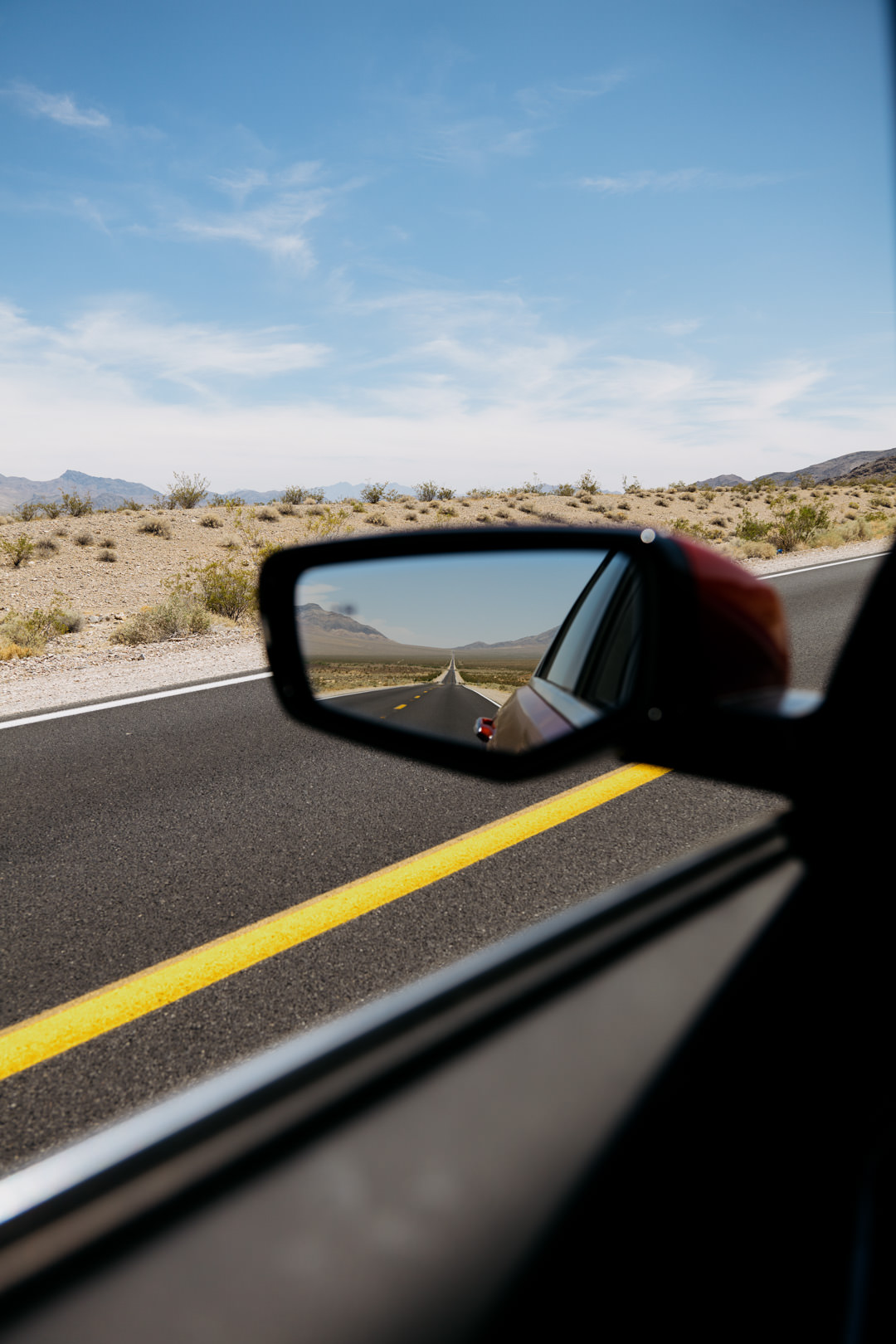 car side mirror with highway in reflection
