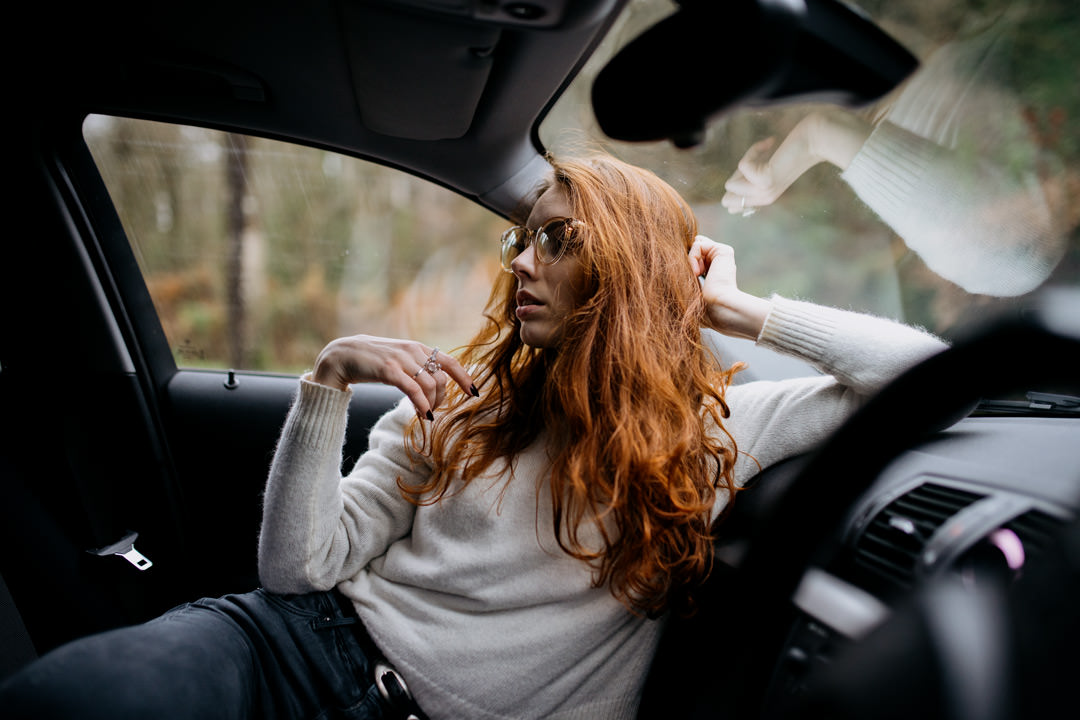 girl with red hair sat in car looking out of window