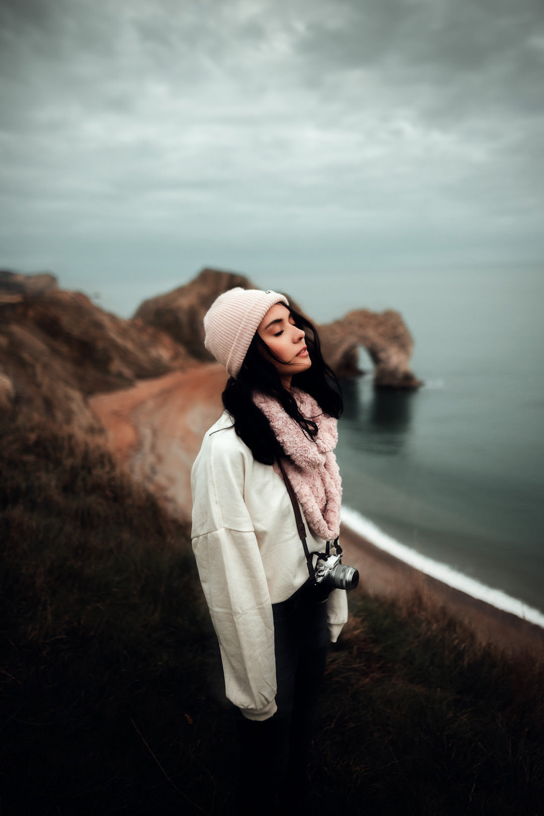 girl stood on cliff edge holding camera