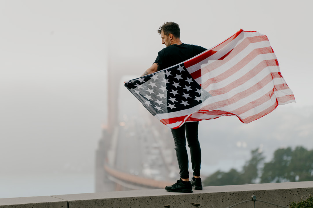 man holding usa flag in city street