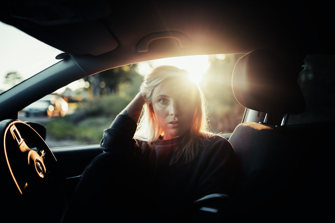 girl sat inside sports car during sunset