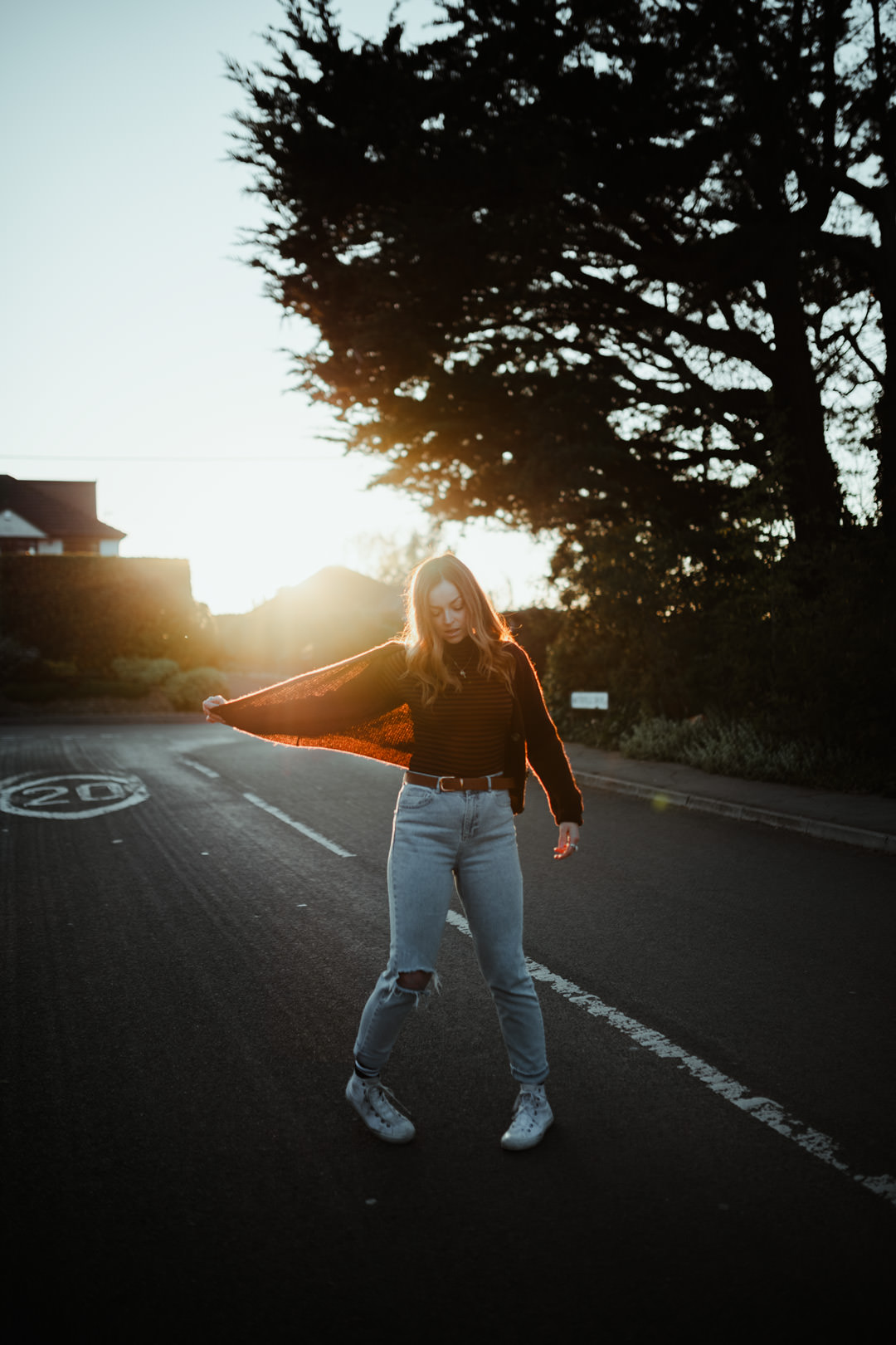 girl dancing in road during golden sunset