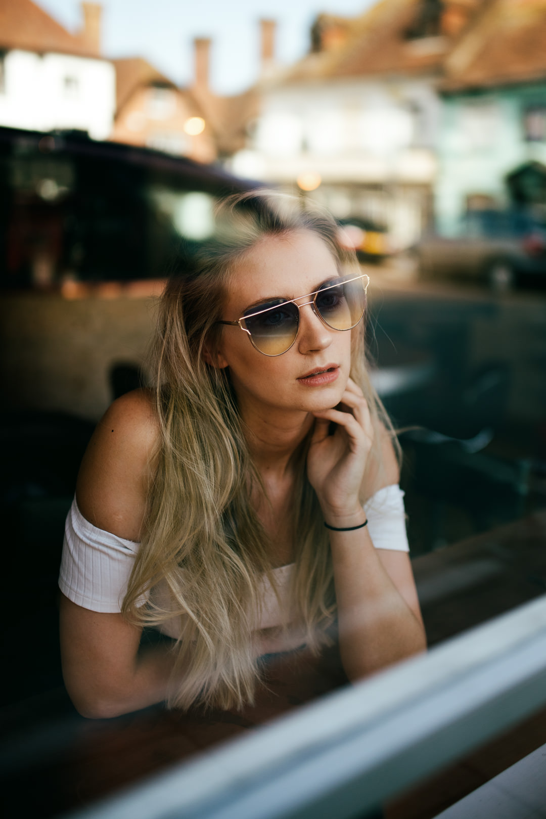 girl waring blue sunglasses sat inside coffee shop window