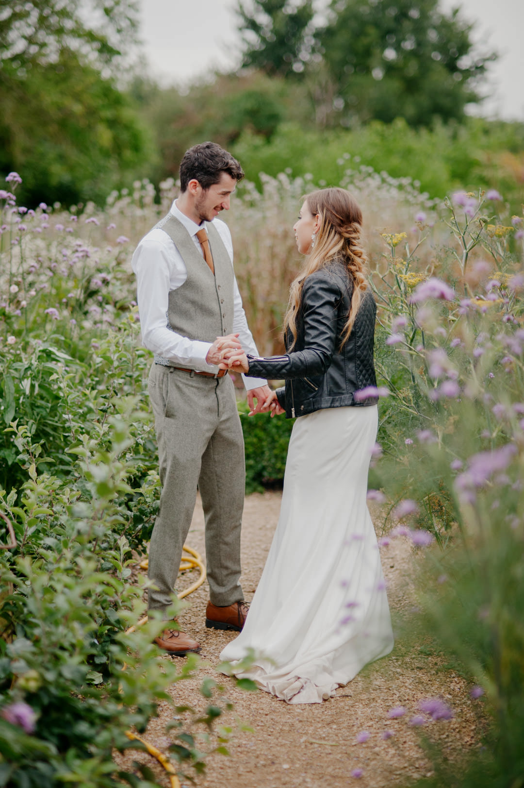 wedding couple holding hands in large floral garden during daytime